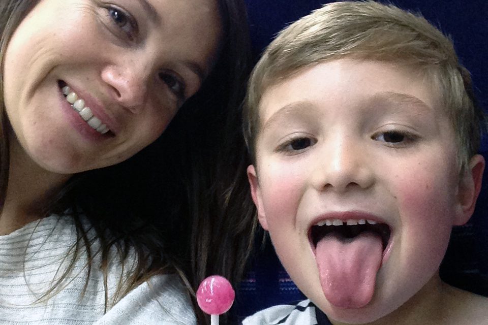 Kelly and Toby sticking out his tongue with a lollipop