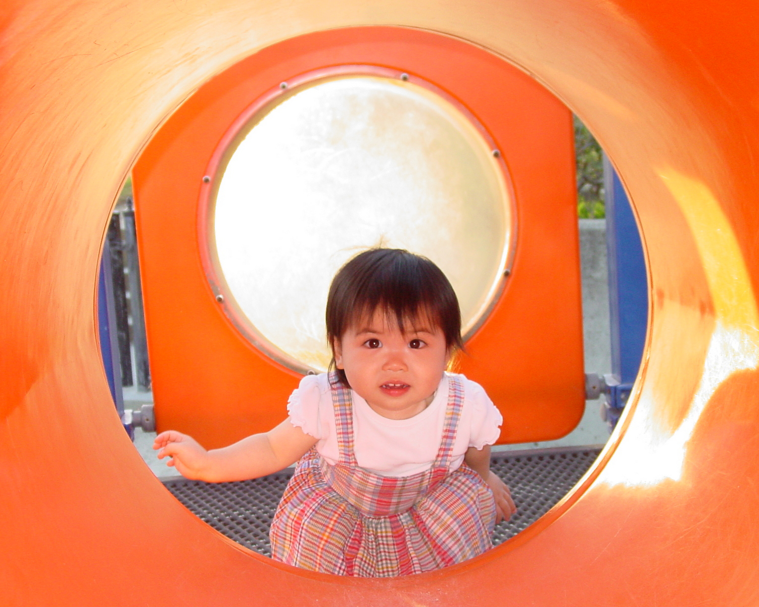 Little girl looking through a play tunnel