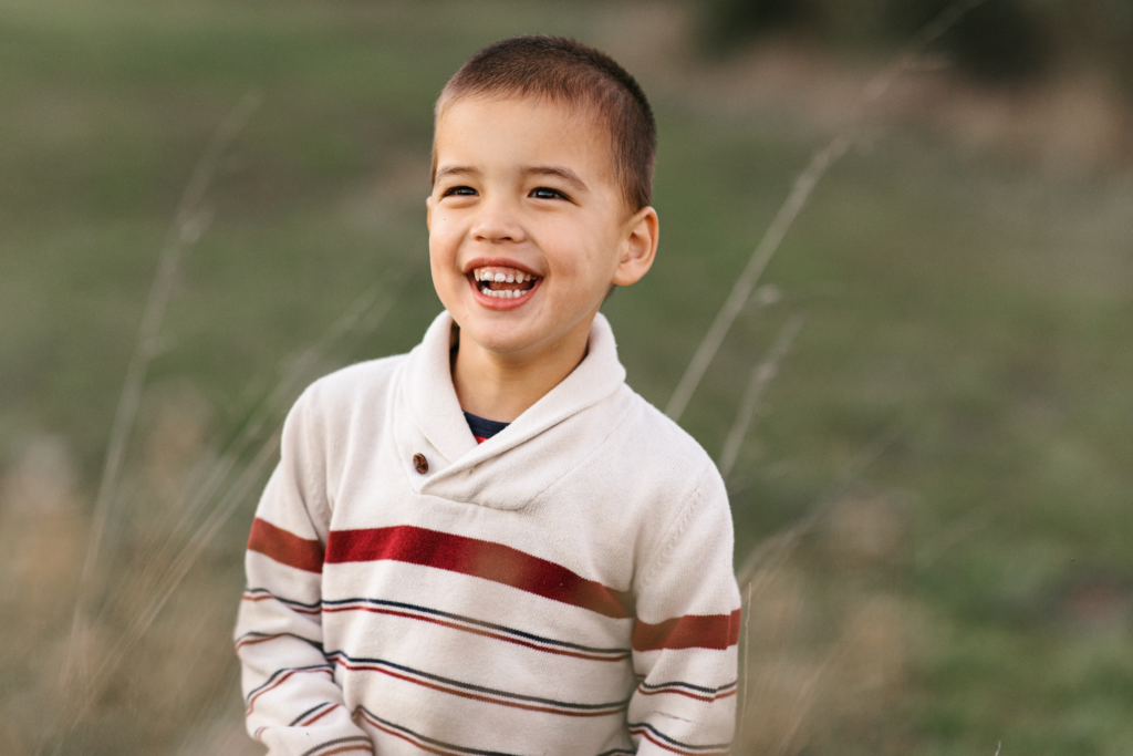 A little boy smiling and looking off into the distance.