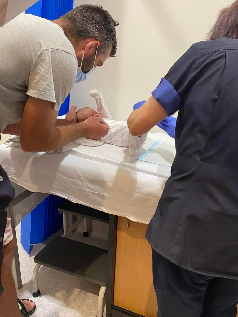 Doctor pricking a newborns foot.