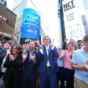 ACD family members and board members cheering in Times Square, with the ACD NASDAQ billboard behind them.